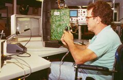 Man with spinal cord injury using a rotating work station to do T.V/VCR repair